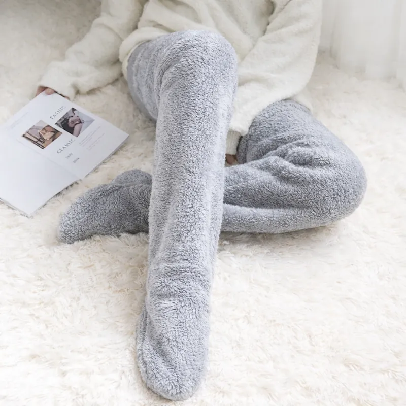 Person relaxing on a rug with a warm drink and sherpa fleece leg warmers to stay warm cheaply