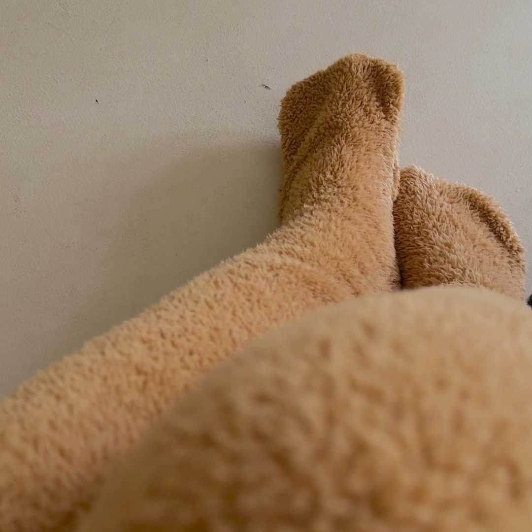 Overhead view of feet and calves in caramel teddy fleece over-the-knee leg warmers on a pale floor