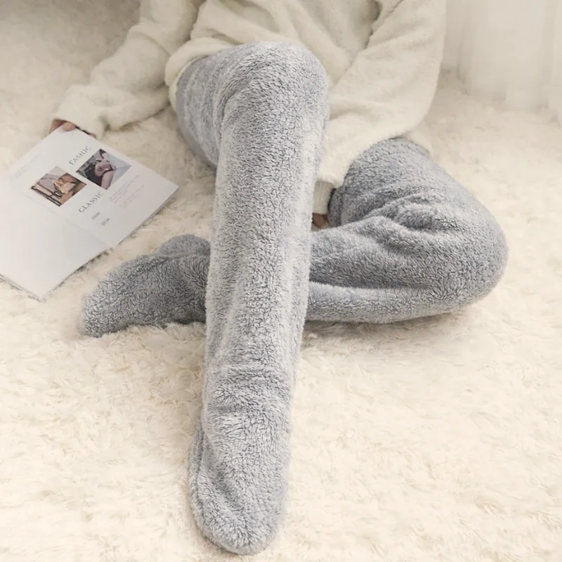 Person lying on a white rug with a magazine, wearing grey sherpa leg warmers