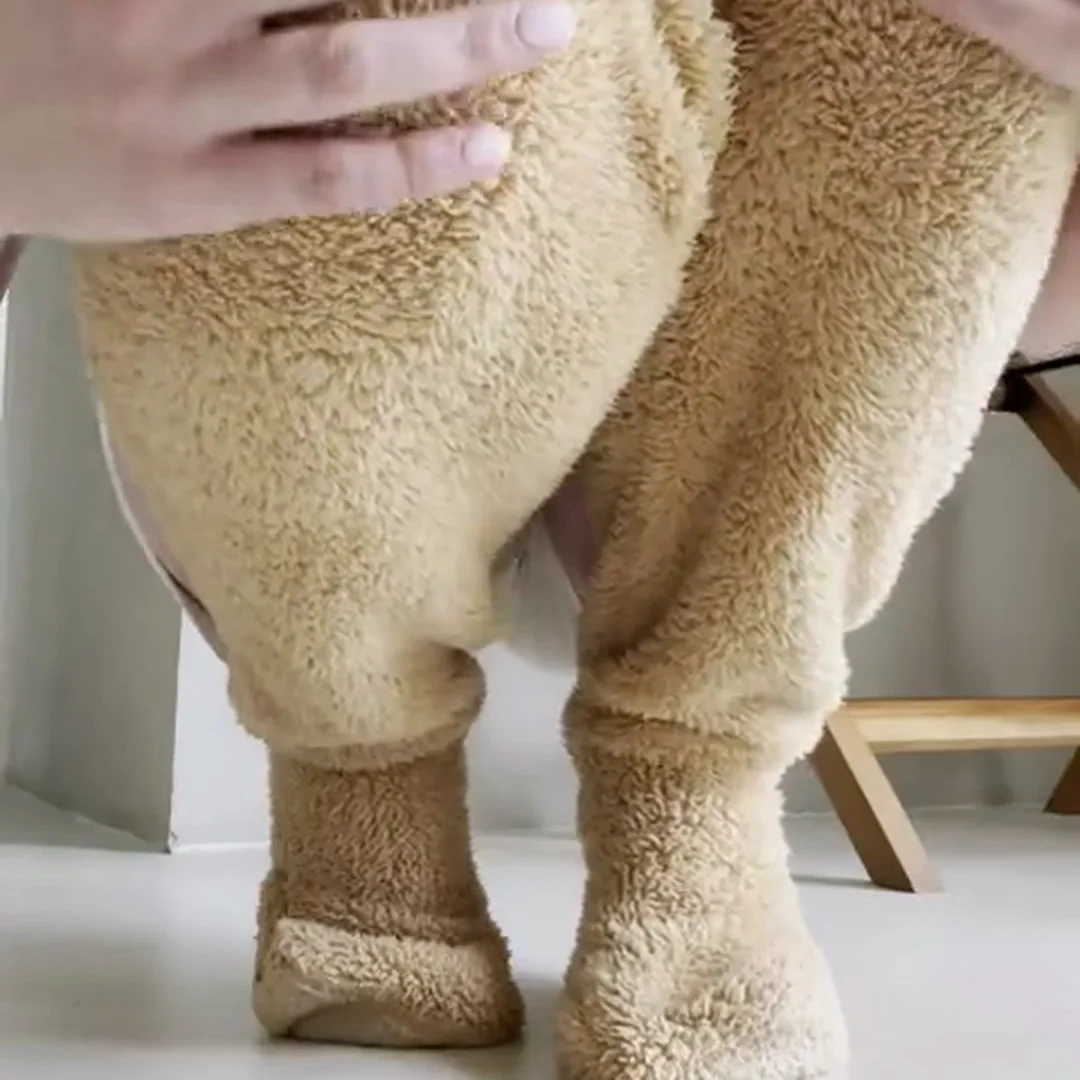 Close-up of teddy fleece leg warmers worn from the thigh down to the covered foot, with a hand pressing into the deep pile